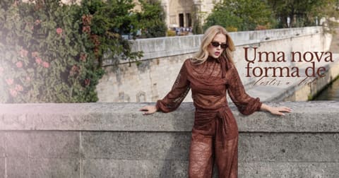 Modelo de blusa e calça de renda marrom apoiada na mureta de uma ponte, com o texto: Uma nova forma de vestir a vida